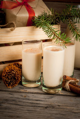 Traditional Christmas alcoholic cocktail - Irish Cream, Cola de mono (monkey tail), decorated with cinnamon. Against the background of Christmas decorations on a wooden table. Close view