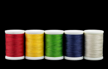 Coils with color threads. Several spools of colored thread on a black background