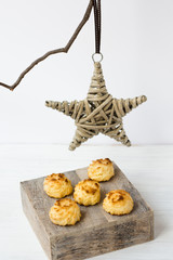 Simple minimalist Christmas decoration rattan star hanging on a dry tree branch, coconut macaroons on a wood box, white background, copyspace, kinfolk style, close up