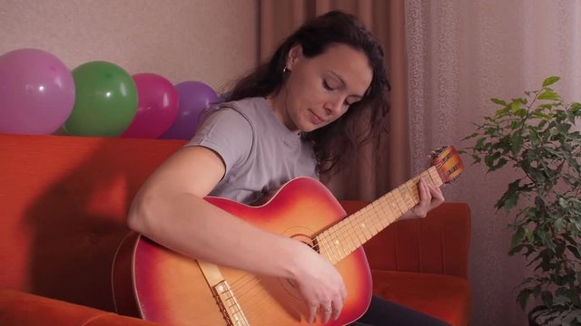 A girl playing on an acoustic guitar