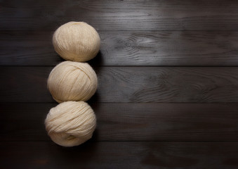 Skeins of white yarn are on a dark wooden table.