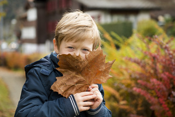 blond boy with autumn leave