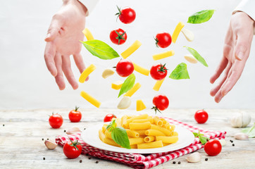 Men's hands with flying pasta with tomato and basil