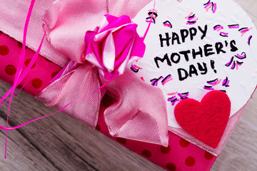 Happy Mother`s Day card inscription. Pink bow on gift box. Greeting handmade composition. Send best wishes.