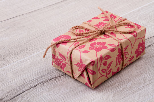 Present box on wooden background. Gift with rope bow. Give presents with joy. Design of holiday package.