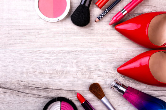 Make-up kit and red shoes. Cosmetics on wooden background. Colorful start of the day. Beauty will save the world.