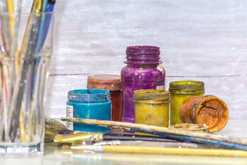 Multicolored plastic cans with paints. Artist workplace background. Old dirty Paints background. Colorful artist palette. Creativity, visual art concept. Art and craft.