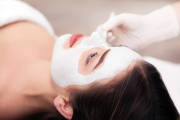Obraz na płótnie Canvas Spa concept. Hand applying nourishing mask on female face in spa salon