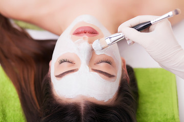 Fototapeta premium Spa Woman applying Facial cleansing Mask. Beauty Treatments. Clay mask