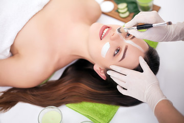 Naklejka premium Spa concept. Hand applying nourishing mask on female face in spa salon