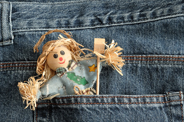 A smiling scare crow figure sticking out of the back of a denim
