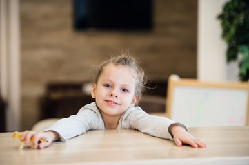 Naklejka premium Beautiful calm little girl sitting at wooden table