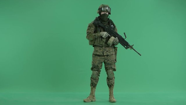 combatant standing and targeting at camera at green screen