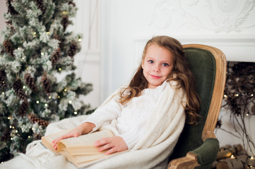 Portrait of 7 years old child reading book at home on christmas