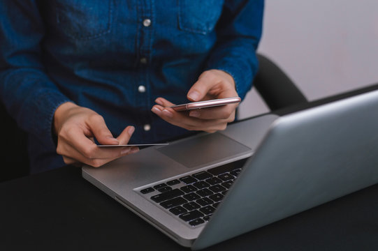 Woman using smartphone app to check e-wallet account balance, close up of hands with mobile phone and plastic credit card