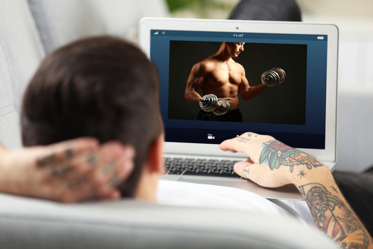 Man watching sport training online on laptop. Fitness and sport blog.