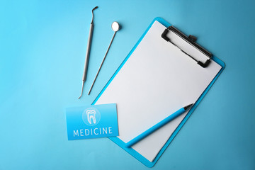 Business card, clipboard and dental tools on blue background. Medical service concept