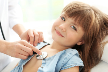 Pediatrician examining little girl's heart