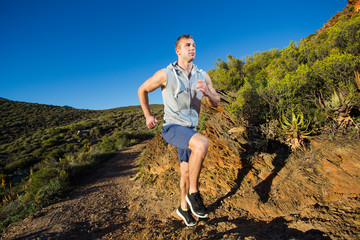 Fototapeta premium Male cross country athlete running in the hills on a warm and su