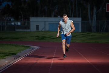 Male sprinter athlete on a tartan athletic track getting ready f