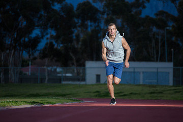 Male sprinter athlete on a tartan athletic track getting ready f