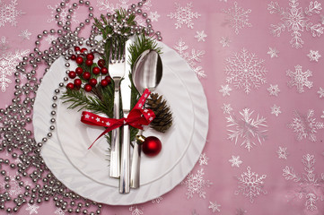 Christmas table place setting with christmas pine branches,ribbon and bow.