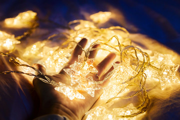 female hand holding a garland of stars warm yellow