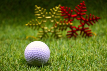 Golf ball with Christmas decoration on green grass