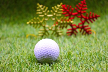 Golf ball with Christmas decoration on green grass