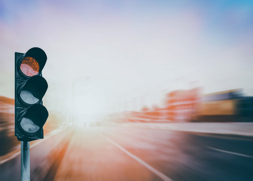 Red traffic light on the expressway asphalt road with car in a city landscape at sunrise. light sign for car stop and speed reduction. Dangerous,warning signal,semaphore driving. Driving on a Highway.
