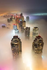 Poster Rare early morning winter fog above the Dubai Marina skyline and skyscrapers ahead of sunrise in Dubai, United Arab Emirates. © Kertu