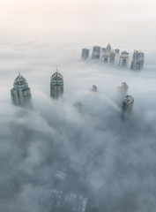 Fototapeta na wymiar Rare early morning winter fog above the Dubai Marina skyline and skyscrapers ahead of sunrise in Dubai, United Arab Emirates.