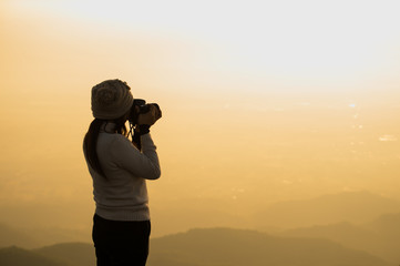 Fototapeta premium Silhouette of photographer taking picture of landscape during sunset, soft and select focus.