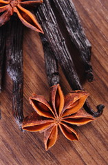 Closeup of star anise and fragrant vanilla on wooden surface plank