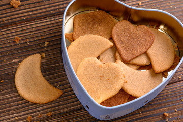 Homemade ginger cookies in heart shaped box on wooden background closeup