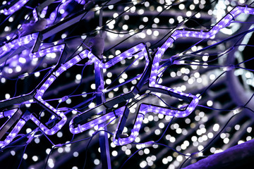 blue christmas lights in shape of snowflakes with blurred lights on background