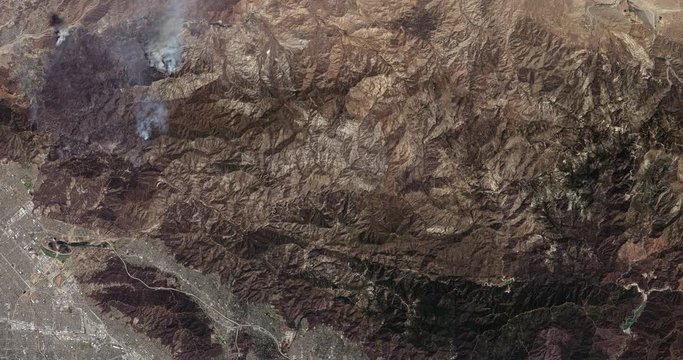 High-altitude overflight aerial of wildfires in San Gabriel Mountains, north of LA. Clip loops and is reversible. Elements of this image furnished by USGS/NASA Landsat 