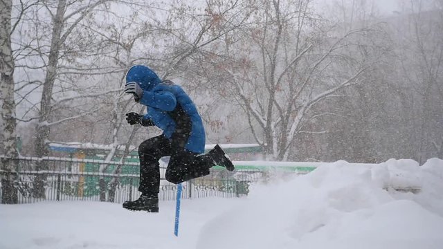 a child jumps into the snow in the winter park. Snow storm