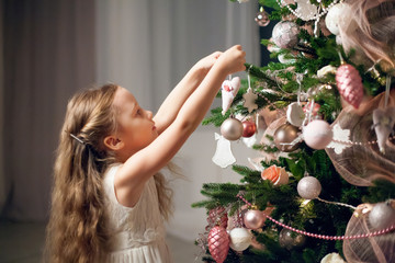 Cute little girl in dress decorating christmas tree