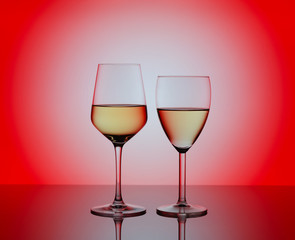  Two wineglasses with white wine on red background