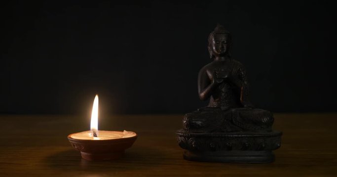 Buddha sculpture near oil candle