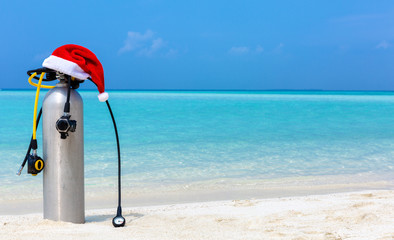 Taucherflasche mit Weihnachtsmütze am tropischen Strand