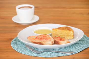 Spanish potato tortilla, bread and sauce served on the plate with a cup of coffee aside
