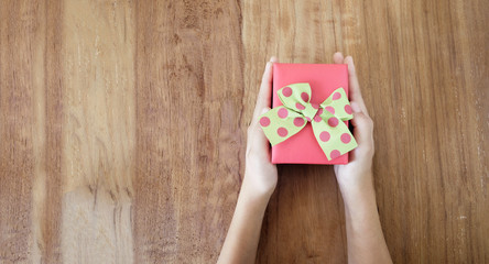 Woman hands holding gift on wooden table