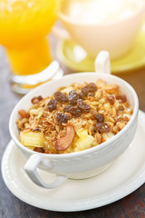 Cereals and grains in ceramic cup with orange juice and hot coffee background on wood table with sunlight.