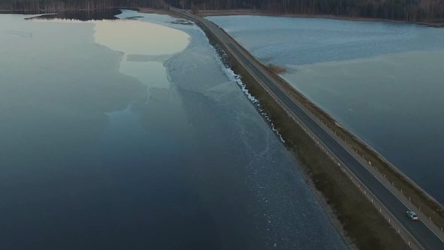 Flight over road in the frozen lake on sunset, winter aerial view.