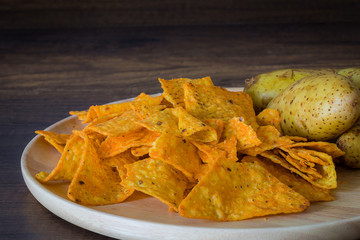 Corn chips with potatoes on the table with nature light in low key tone.