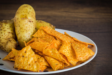 Corn chips with potatoes on the table with nature light in low key tone.