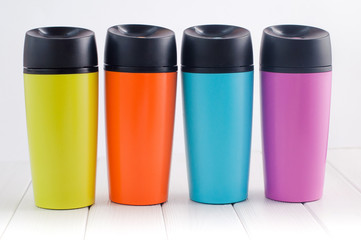 Color thermos mugs on the white wooden table