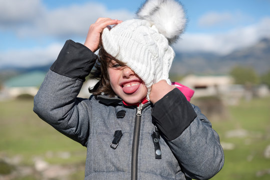 Close-up of a little girl with wool cap and scarf in the field